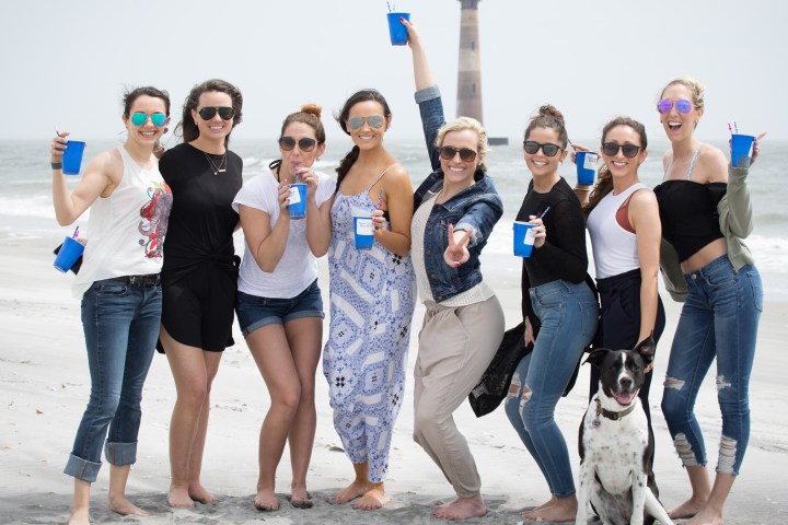 Women holding cups on beach