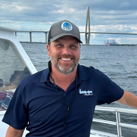 a man holding a fish on a boat in a body of water