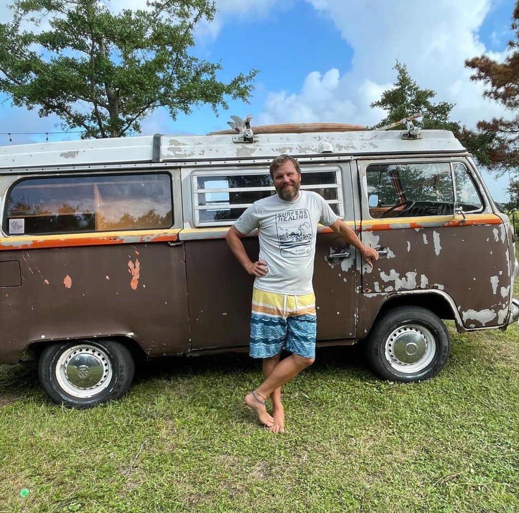 a person standing in front of an old truck parked next to a car