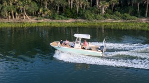 Small boat with people moving on a river near a forested shore.