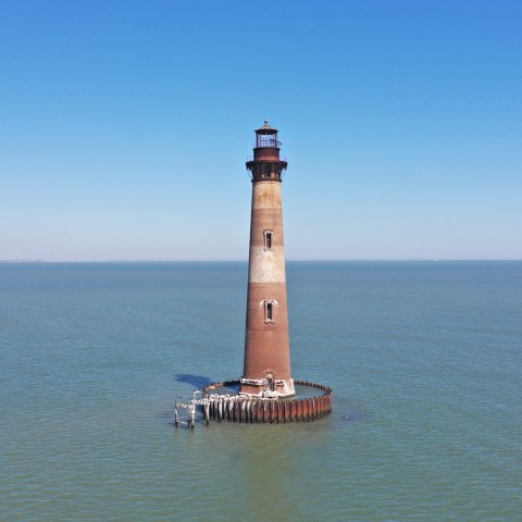 a extremely old lighthouse next to a body of water