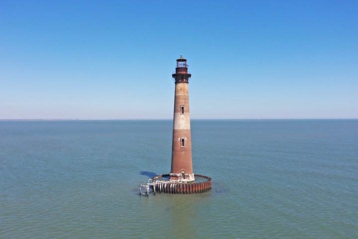 a extremely old lighthouse next to a body of water