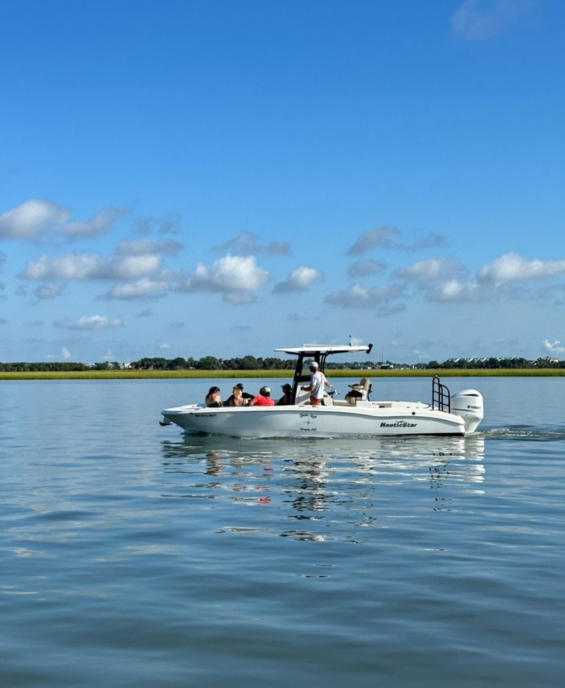 A boat with people on a calm lake under a clear blue sky.