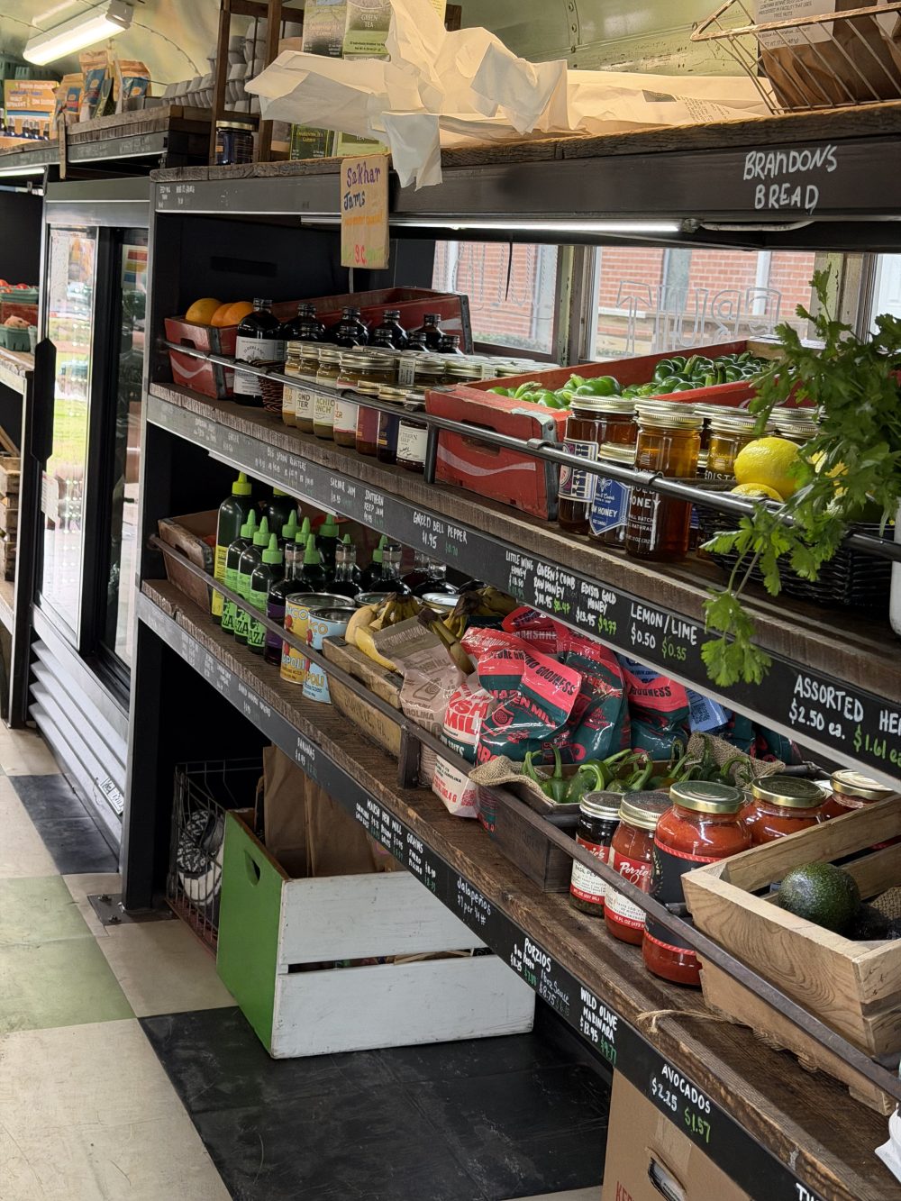 Grocery shelves with various food items, fresh produce, and jars in a market setting.