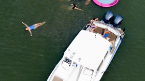People swimming near a boat and a large pink float in water.