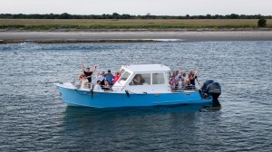 Group of people waving on a blue boat in a river.